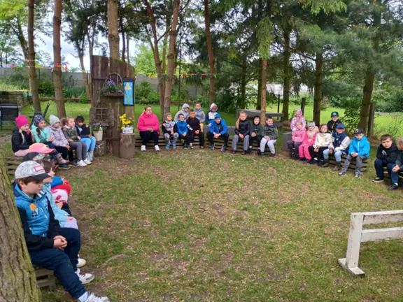 Uczniowie klasy 1a i 1c siedzą w kręgu w oczekiwaniu na zajęcia z psem