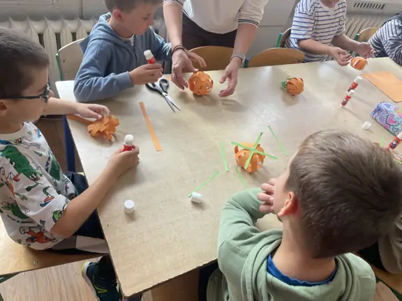 Dzieci tworzą jesienne prace według instrukcji nauczyciela