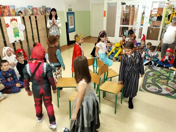 Uczestnicy zabawy spacerują wokół krzeseł.