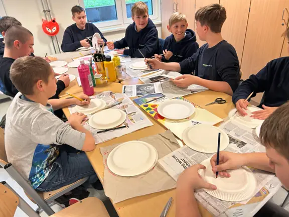 Uczniowie robią z papieru lampiony.