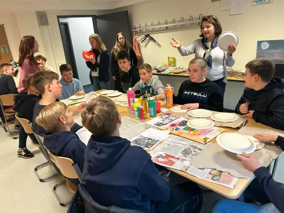 Grupa uczniów robi z papieru lampiony.