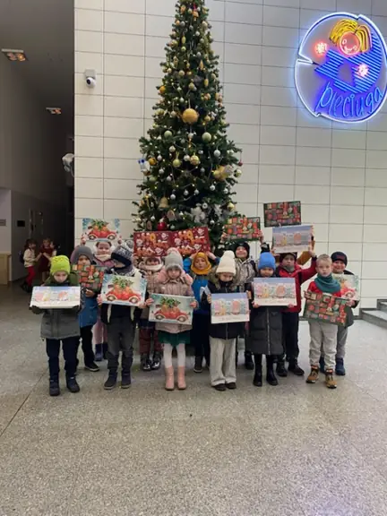 Dzieci z klasy pierwszej a stoją przy choince a w rękach mają kalendarze adwentowe