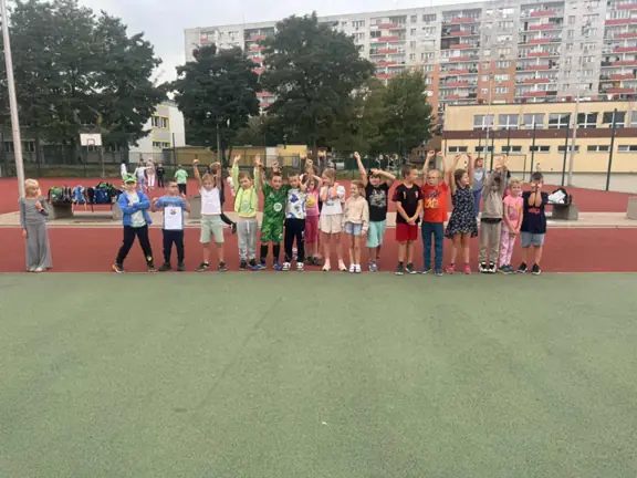 Uczniowie grają w piłkę nożną na boisku szkolnym