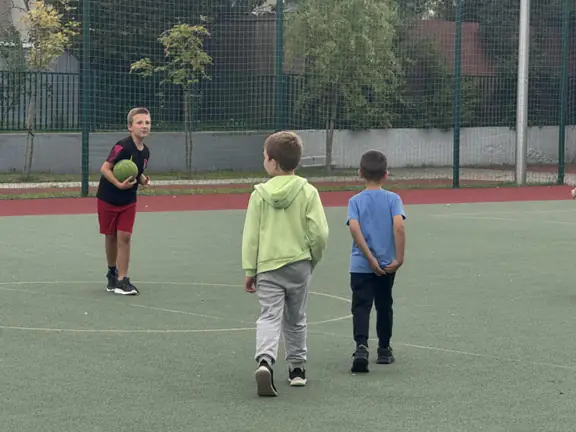 Uczniowie grają w piłkę nożną na boisku szkolnym
