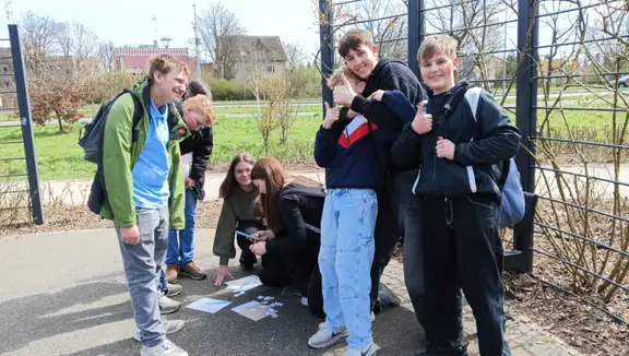 Uczniowie w parku układają puzzle.