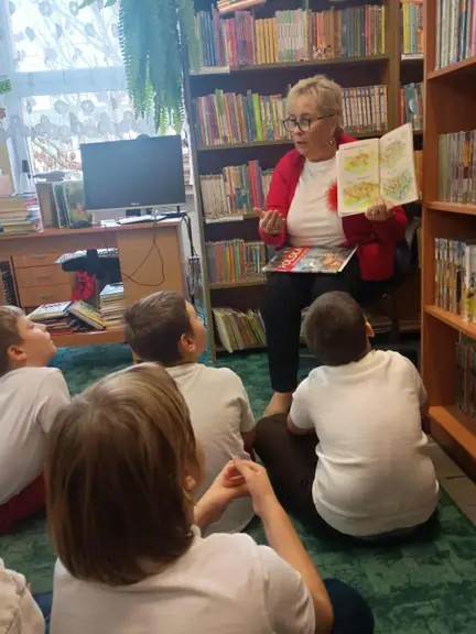 Pani bibliotekarka opowiada dzieciom z kl. IIa o początkach państwa polskiego i pokazuje ilustracje.