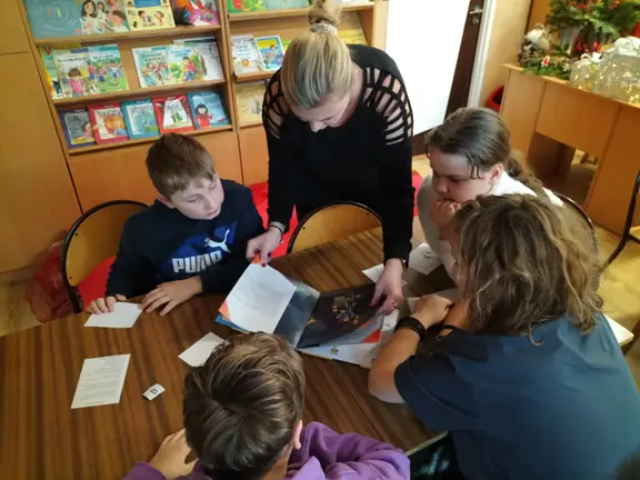 pani-agnieszka-oglada-ksiazke-i-pomaga-uczniom-w-zdobyciu-informacji--jpg