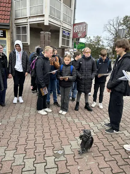uczeń stoi przy gryfiku na Placu Wolności w Stargardzie a obok niego stoją słuchający go uczniowie z Niemiec