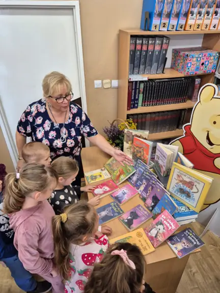 Pani bibliotekarka pokazuje dzieciom książki o kotach dla dzieci.