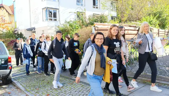 Uczniowie idą chodnikiem i uśmiechają się do aparatu.