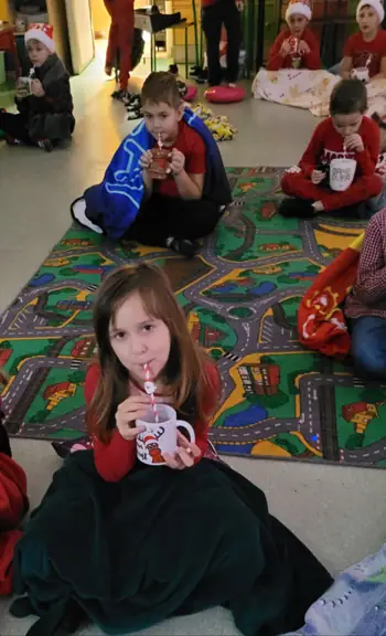 Dzieci z kl. IIa siedzą pod kocykami i piją ciepłe kakao.