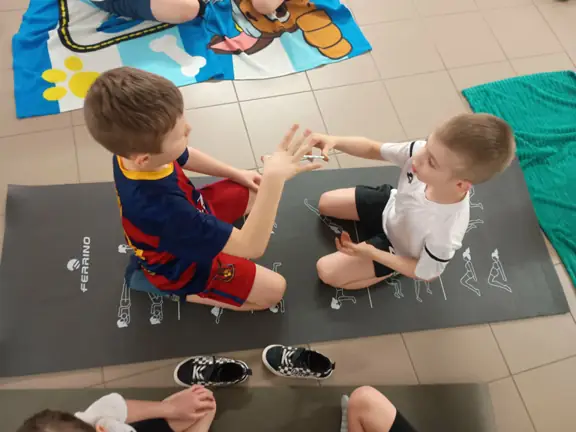 dwoch-chlopcow-wykonuje-na-macie-cwiczenie-ze-slomka-jpg