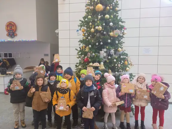 Dzieci z klasy pierwszej a stoją przy choince a w rękach mają prezenty od Mikołaja