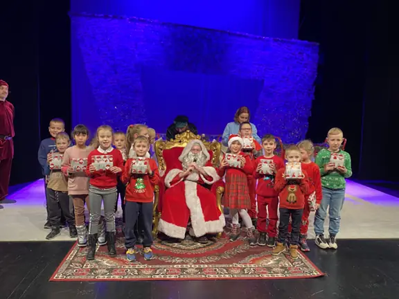 Dzieci z klasy pierwszej c pozują do zdjecia z Mikołajem na scenie Teatru Lalek Pleciuga