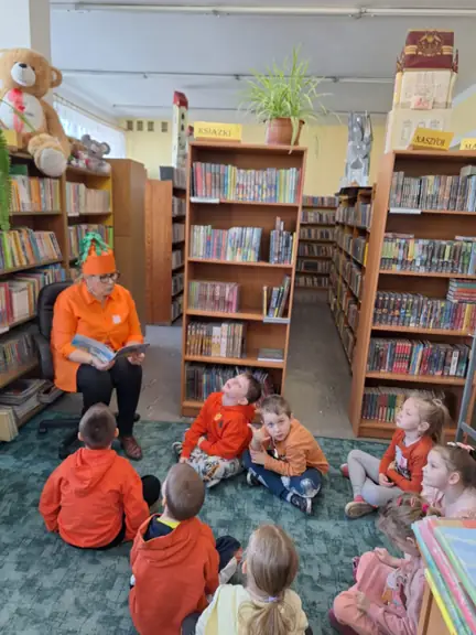 Pani bibliotekarka czyta dzieciom książeczkę pt. Przyjęcie u Karoliny z serii Marchewkowy ogród.