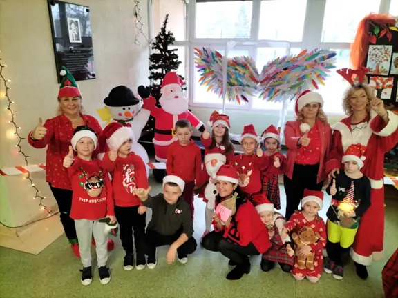 Dzieci pozdrawiają Mikołaja machając rączkami.