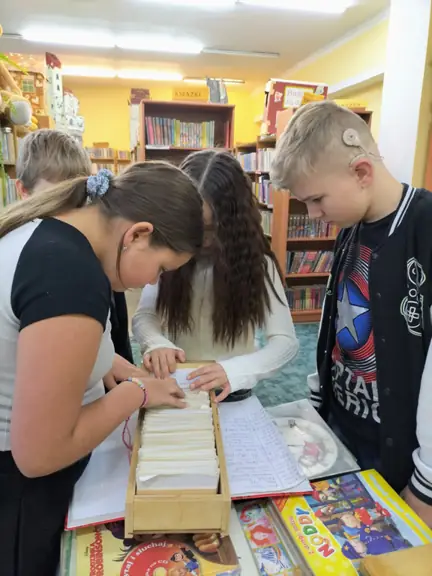 Jedna z grup dzieci wyszukuje karty katalogowej w katalogu alfabetycznym.