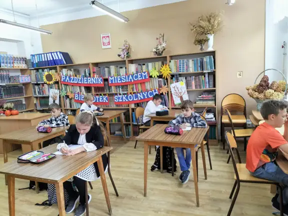 Dzieci siedzą przy stolikach i zapoznają się z zadaniami konkursowymi.