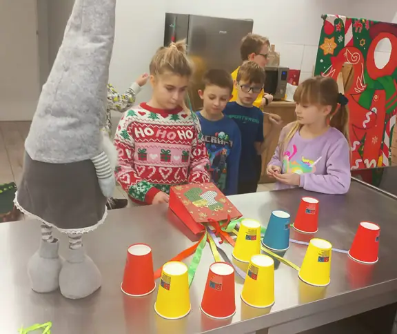 Grupa dzieci szuka słodyczy pod kubeczkami