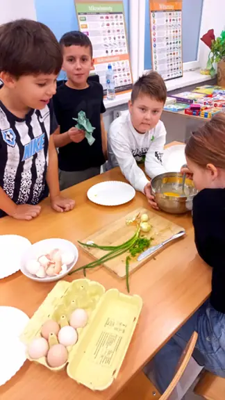 Rozbijanie jajej przez uczniów do miski.