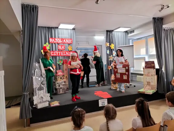 Krasnoludek pokazuje dzieciom zniszczoną książkę.