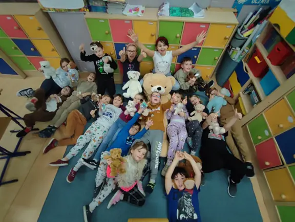 Uczniowie kl. IIb pozują z misiami do zdjęcia.