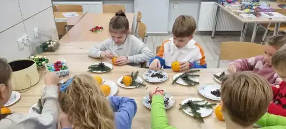 Dzieci  dekorują pomarancze goździkami 