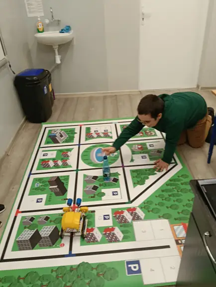 uczeń układa na specjalnej macie przeszkody dla robota SkriBot