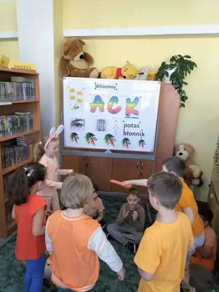 Dzieci z grupy 01 bawią się przy muzyce podając marchewkę z ręki do ręki.