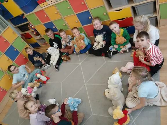 Dzieci z kl. Ic siedzą w kręgu z misiami.