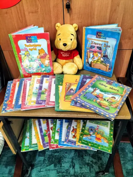 Zestaw książek z różnymi przygodami Kubusia Puchatka w kąciku czytelniczym.