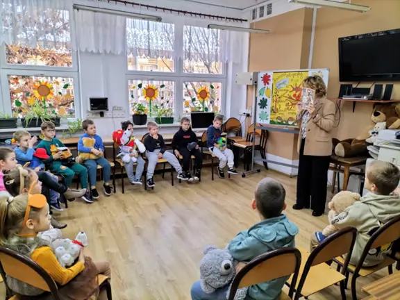 Pani bibliotekarka prezentuje dzieciom z kl. Ib książkę Przygody Misia Uszatka.