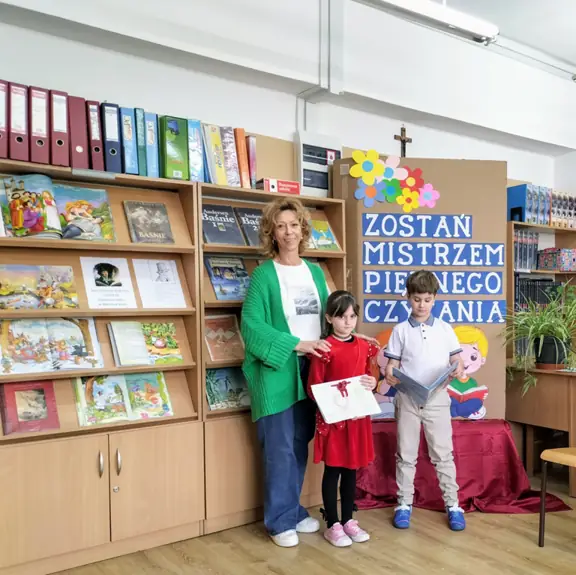 Uczeń kl. Ia czyta fragment bajki, jego koleżanka prezentuje klasową książeczkę.