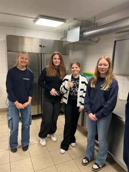 Cztery dziewczynki pozują w kuchni szkolnej do zdjęcia.