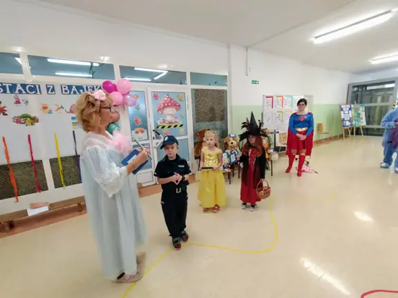 Pani bibliotekarka przekazuje dzieciom bajki do wspólnego czytania podczas zajęć lekcyjnych.