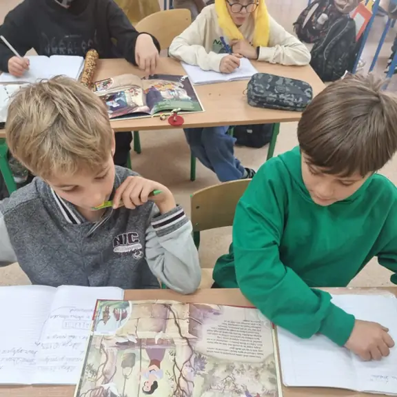 Chłopcy zapisują w zeszytach informacje o bohaterach bajki.
