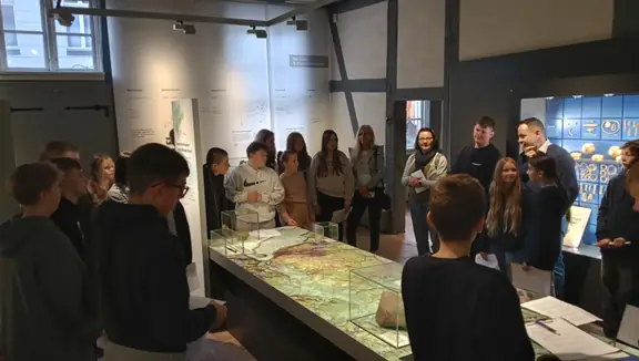 Uczniowie stoją dookoła stołu- makiety w muzeum.