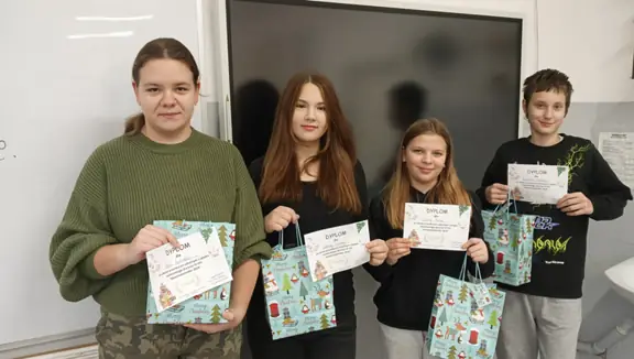 Czworo uczniów pozuje z dyplomami i nagrodami do wspólnego zdjęcia