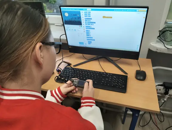 uczennica tworzy w mBlock projekt gry - strzelanka w kosmosie, używając przy tym kontrolera CyberPi