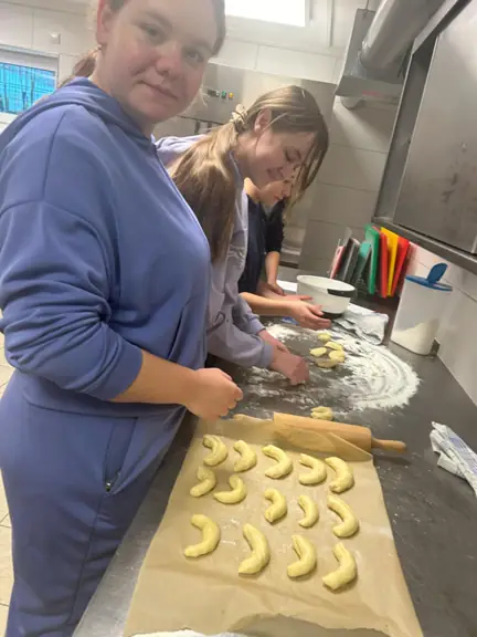 Dwie uczennice robią z ciasta rogaliki.
