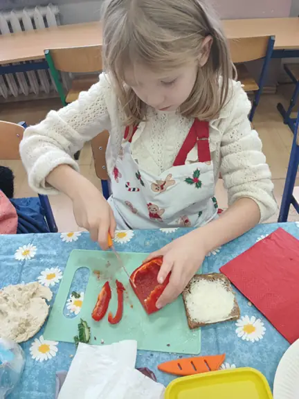 Uczennica kroi warzywa.