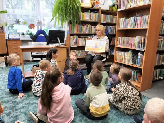 pani-bibliotekarka-rozmawia-z-dziecmi-na-temat-przezyc-tupcia-chrupcia-i-pokazuje-ilustracje-do-opowiadania-tupcio-chrupcio--umiem-sie-dzielic--jpg