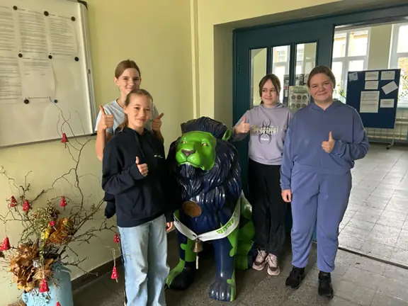 Cztery uczennice pozują do zdjęcia w holu szkoły.