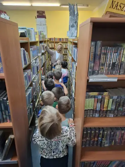 Pani bibliotekarka pokazuje dziecim z grupy 01 Biedronki księgozbiór biblioteki