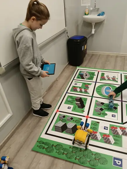 uczeń steruje robotem SkriBot na specjalnej macie