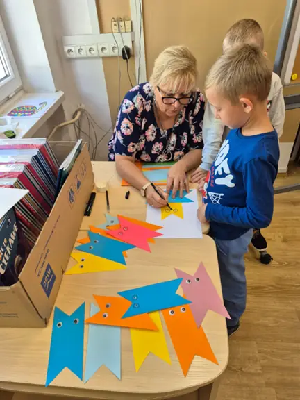 Pani bibliotekarka pomaga w wykonaniu głowy kota.