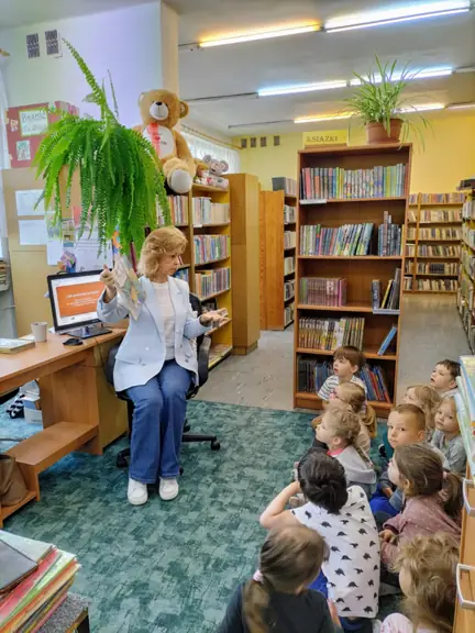 Pani bibliotekarka pokazuje dzieciom ilustracje w książce.