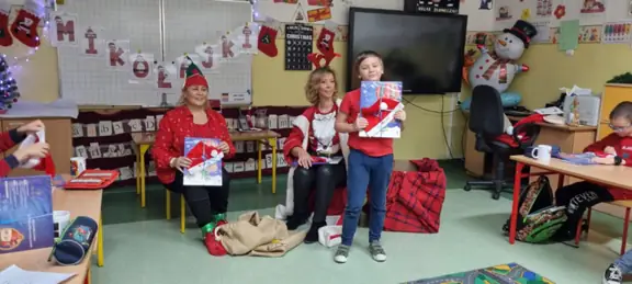 Panie bibliotekarki wręczają podarunki od Mikołaja uczniom z kl. IIa. 