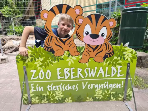 Uczeń pozuje przy banerze ZOO