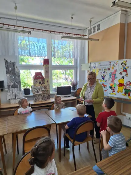 Pani bibliotekarka odczytuje wylosowaną przez dziecko bajkową zagadkę.